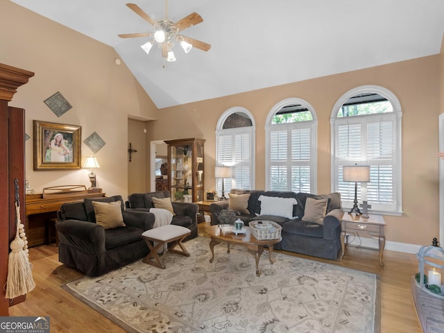 living room featuring a ceiling fan, high vaulted ceiling, and wood finished floors