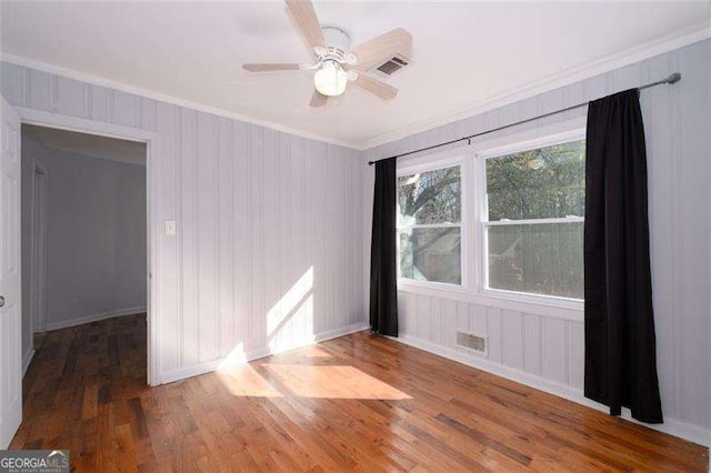 unfurnished room with a ceiling fan, ornamental molding, visible vents, and wood finished floors
