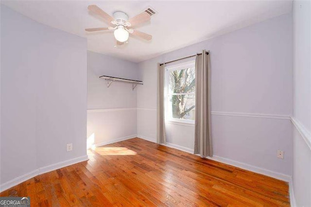 spare room featuring baseboards, a ceiling fan, visible vents, and wood finished floors