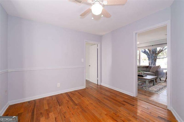 spare room featuring wood finished floors, baseboards, and a ceiling fan