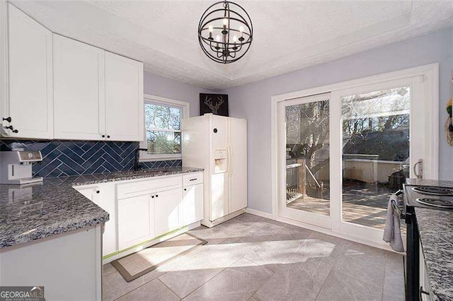 kitchen featuring white fridge with ice dispenser, a notable chandelier, white cabinets, electric range, and a textured ceiling