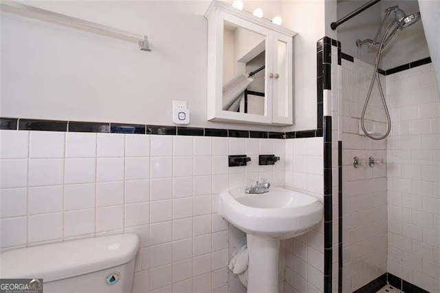 bathroom with a stall shower, tile walls, and toilet