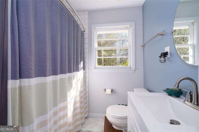 bathroom with toilet, baseboards, a healthy amount of sunlight, and vanity