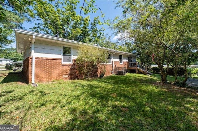 back of house featuring a yard, stairs, and brick siding