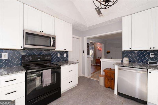 kitchen featuring lofted ceiling, white cabinets, dark stone counters, and appliances with stainless steel finishes
