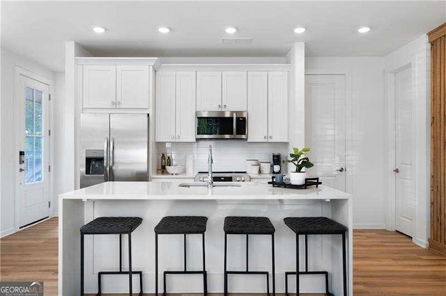 4856 Allatoona Unit 8, Acworth, GA 30101 - kitchen featuring a kitchen bar, white cabinetry, wood finished floors, stainless steel appliances, and an island with sink