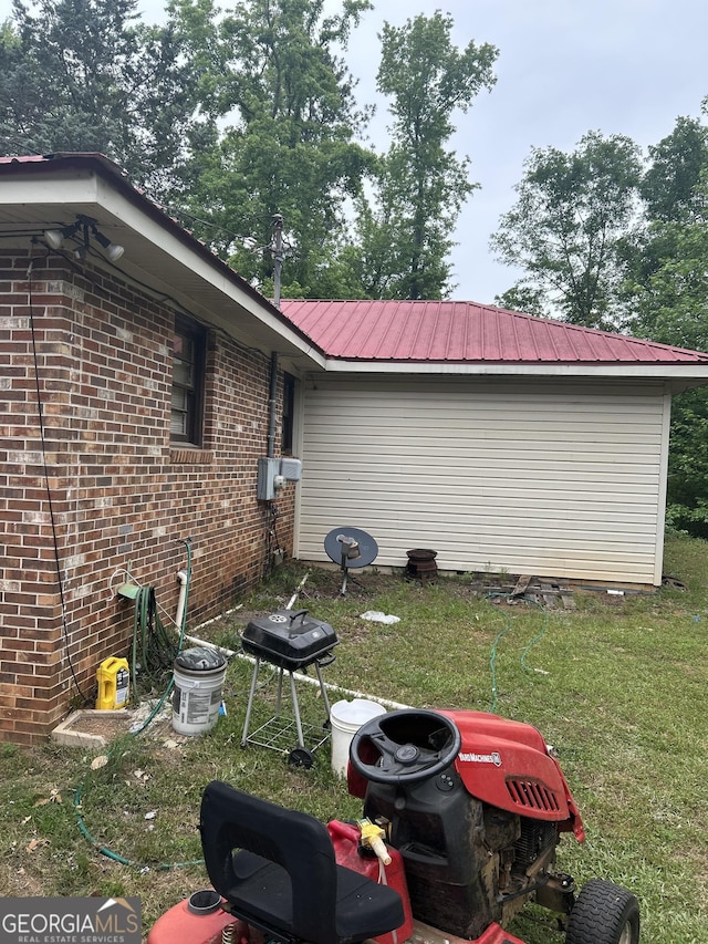 view of home's exterior with a yard, metal roof, and brick siding