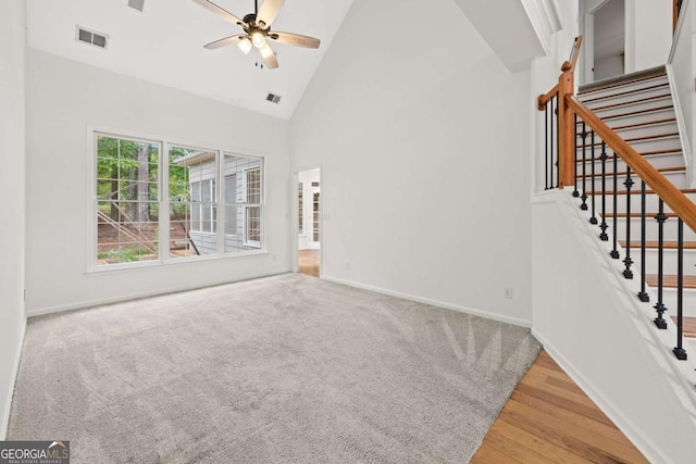 unfurnished living room featuring baseboards, ceiling fan, stairs, high vaulted ceiling, and wood finished floors