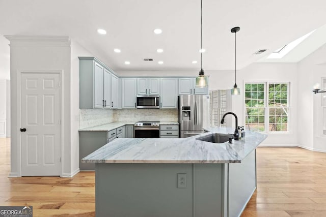 kitchen featuring gray cabinetry, light wood-type flooring, stainless steel appliances, and a sink