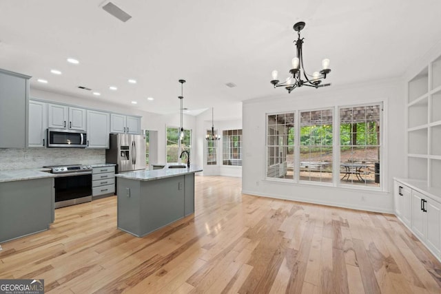 kitchen featuring light wood-style flooring, an inviting chandelier, appliances with stainless steel finishes, and a sink