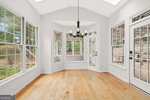 unfurnished sunroom with an inviting chandelier, french doors, lofted ceiling with skylight, baseboards, and hardwood / wood-style flooring