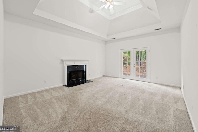 unfurnished living room with a tray ceiling, carpet, visible vents, and ceiling fan