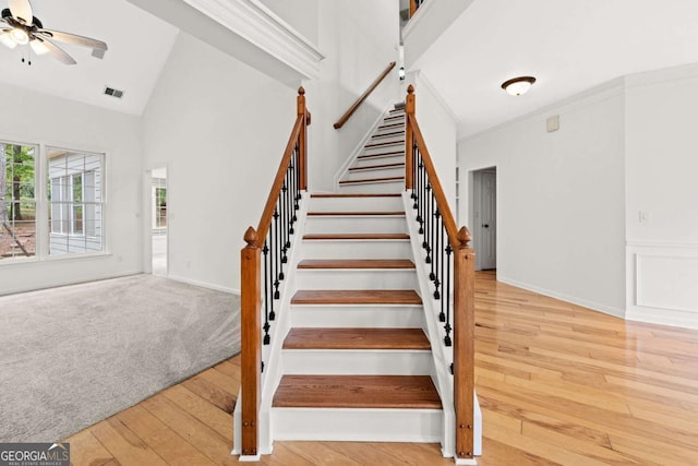 stairway with hardwood / wood-style flooring, high vaulted ceiling, visible vents, a ceiling fan, and baseboards