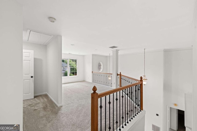 hallway with carpet, an upstairs landing, attic access, visible vents, and baseboards