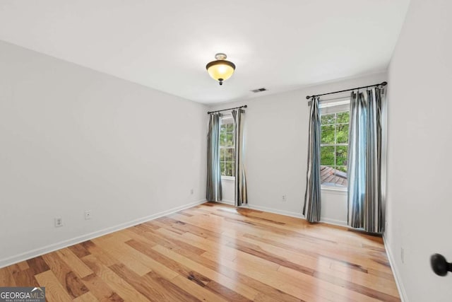 spare room featuring baseboards, visible vents, and light wood-style floors