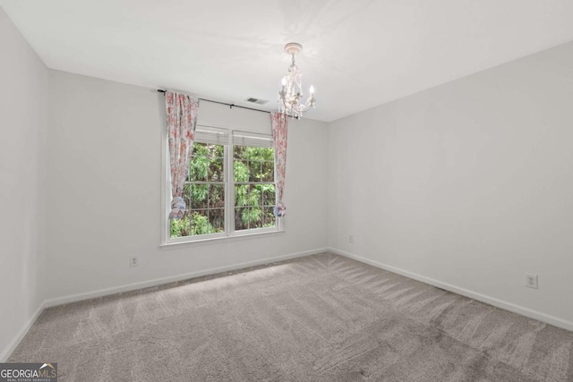 carpeted empty room with baseboards and an inviting chandelier