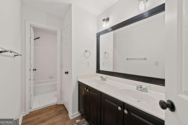 bathroom featuring double vanity, wood finished floors, shower / tub combination, and a sink