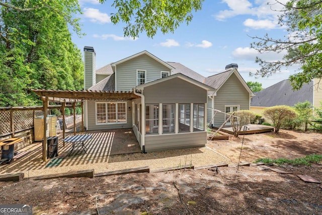 back of property featuring a chimney, a patio, a sunroom, a pergola, and a deck
