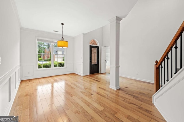 unfurnished dining area with stairs, light wood finished floors, visible vents, and ornate columns