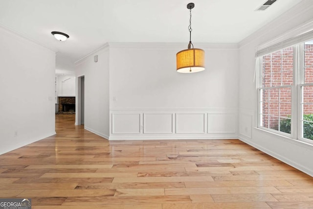 unfurnished dining area featuring light wood finished floors, crown molding, and visible vents