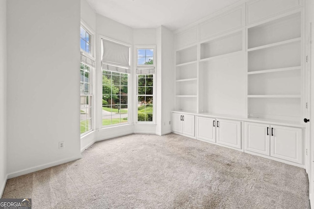 interior space featuring built in shelves, baseboards, and carpet floors