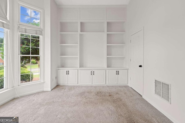 interior space with light colored carpet, baseboards, visible vents, and built in features