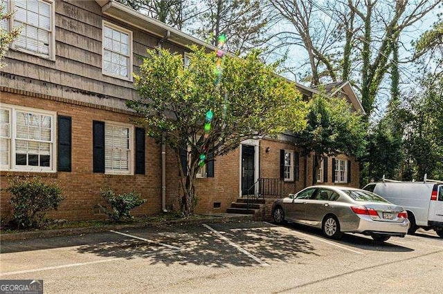 view of home's exterior with brick siding and uncovered parking