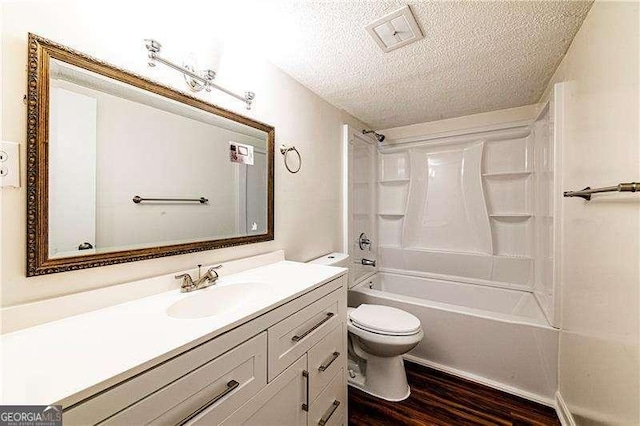 bathroom featuring shower / bathing tub combination, toilet, wood finished floors, vanity, and a textured ceiling