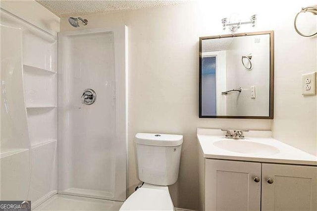 full bathroom with vanity, toilet, a stall shower, and a textured ceiling