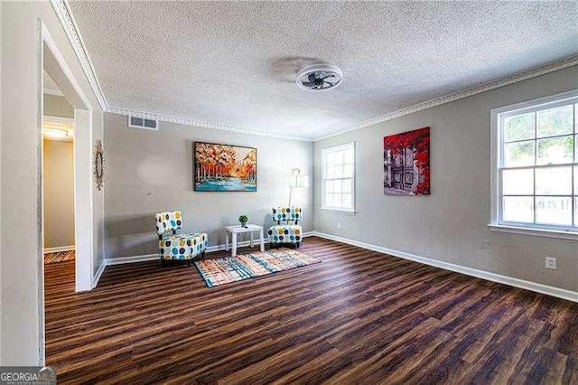 living area featuring baseboards, ornamental molding, a textured ceiling, and wood finished floors