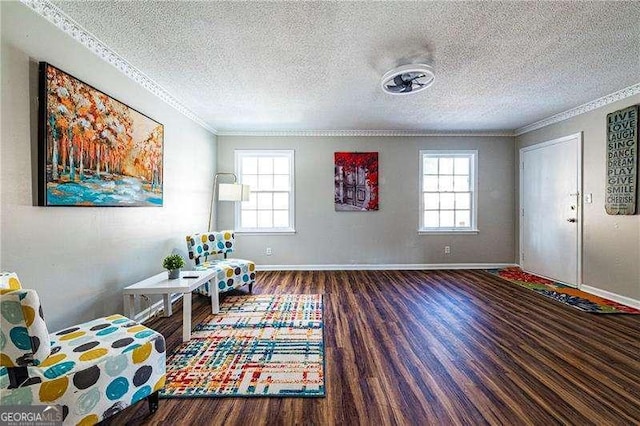 sitting room with crown molding, a textured ceiling, wood finished floors, and baseboards