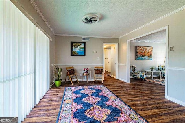 sitting room featuring crown molding, a textured ceiling, visible vents, and wood finished floors