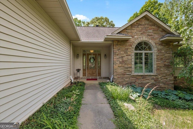 property entrance featuring roof with shingles and stone siding