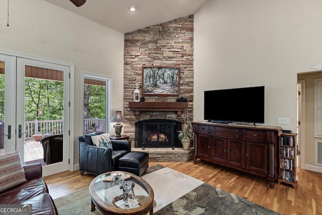 living area featuring light wood finished floors, a fireplace, high vaulted ceiling, and visible vents