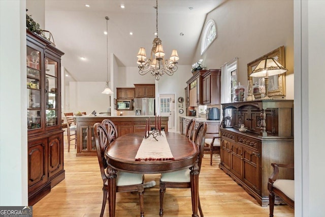 dining area featuring a notable chandelier, high vaulted ceiling, and light wood-style floors