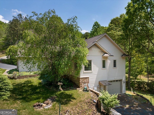 view of property exterior with a yard, driveway, and an attached garage