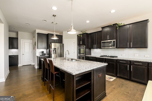 kitchen featuring stainless steel appliances, a sink, dark wood-style floors, decorative backsplash, and recessed lighting