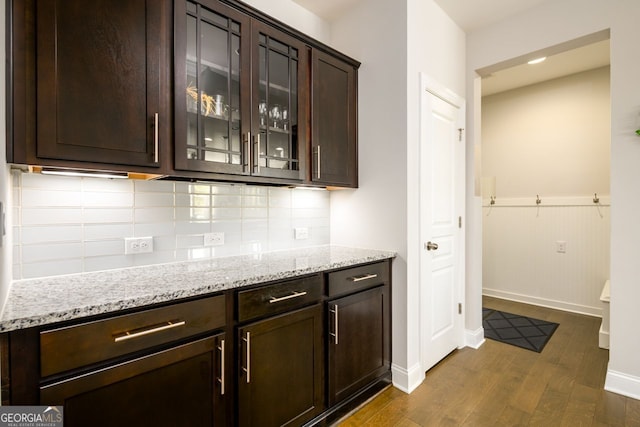 bar with dark wood finished floors, decorative backsplash, baseboards, and wainscoting
