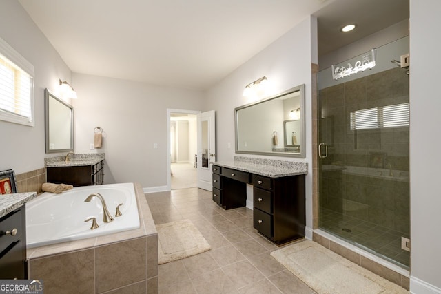 full bathroom featuring a shower stall, a bath, tile patterned flooring, two vanities, and baseboards