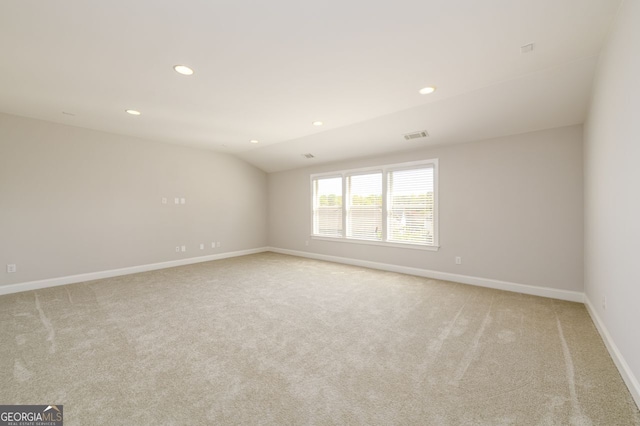 empty room with light carpet, vaulted ceiling, baseboards, and recessed lighting