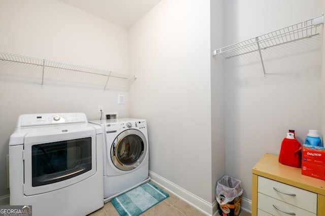 laundry area with washing machine and clothes dryer, baseboards, and light tile patterned flooring