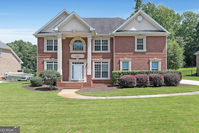greek revival house with a front yard and brick siding
