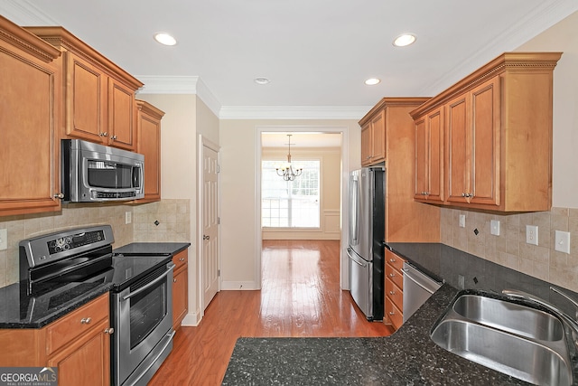 kitchen featuring a sink, stainless steel appliances, a chandelier, crown molding, and light wood-style floors