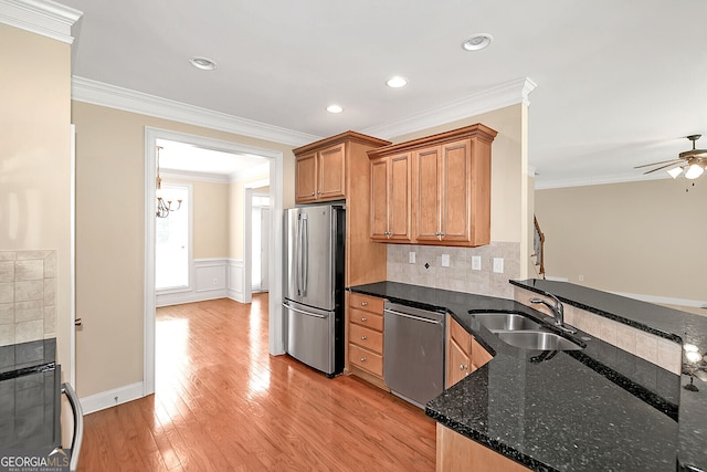 kitchen with a sink, ornamental molding, light wood-type flooring, and appliances with stainless steel finishes