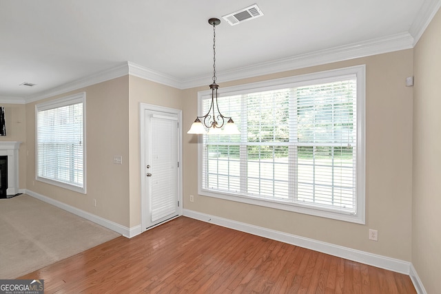 unfurnished dining area featuring baseboards, ornamental molding, visible vents, light wood-style floors, and a fireplace