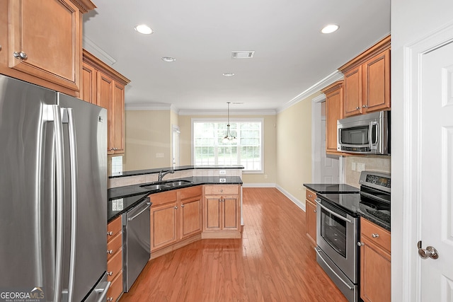 kitchen with ornamental molding, a peninsula, appliances with stainless steel finishes, and a sink