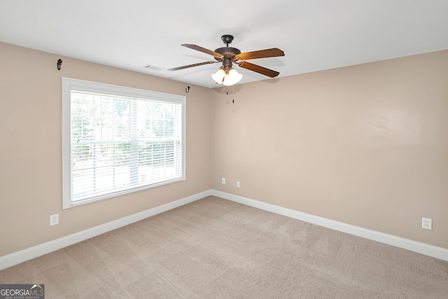 unfurnished room with light colored carpet, visible vents, baseboards, and ceiling fan