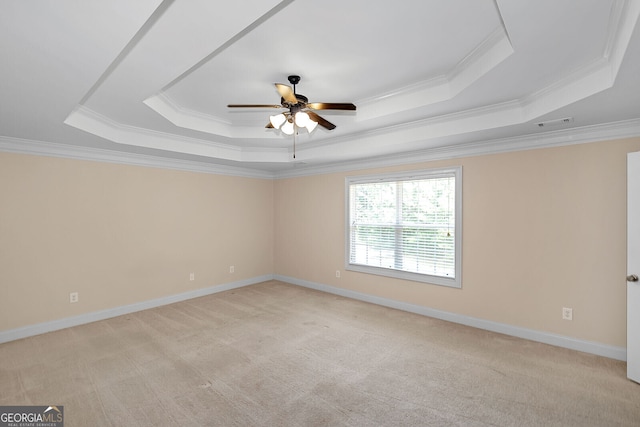 spare room with a tray ceiling, crown molding, light carpet, and a ceiling fan