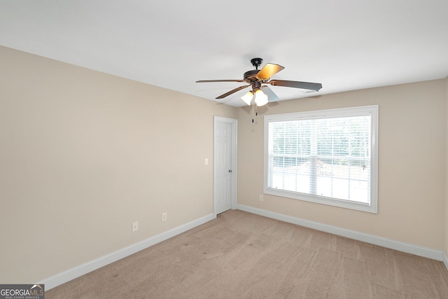 spare room featuring light colored carpet, baseboards, and a ceiling fan