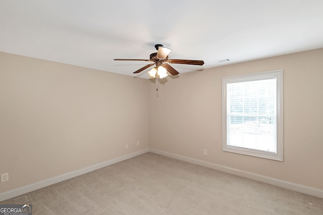 unfurnished room with light colored carpet, visible vents, baseboards, and a ceiling fan